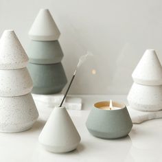 three white and gray candles sitting next to each other on top of a table with one candle in the middle