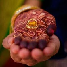 a close up of a person holding a ring on their finger and wearing a henna