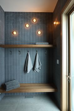 two towels are hanging on a shelf in the bathroom, with three lights above it