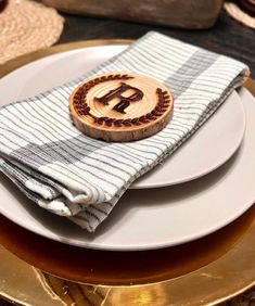 a white plate topped with a wooden monogrammed napkin