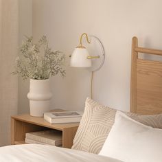 a bedroom with a bed, lamp and flowers on the nightstand next to the bed