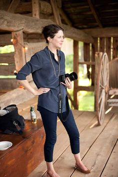 a woman is standing on a porch with a camera in her hand and she is looking at something