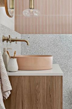 a bathroom sink sitting under a mirror next to a wooden cabinet and light fixture on the wall