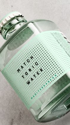 a close up of a bottle of water on a white surface with the words match tonic water written on it