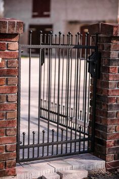 an iron gate is open on the side of a brick building with a fire hydrant in it