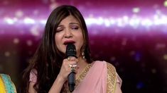 a woman in a pink sari holding a microphone