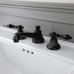 two black faucets sitting on top of a white sink