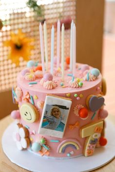 a pink birthday cake decorated with pictures and candles