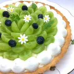 a green and white cake with blueberries on top is sitting on a platter