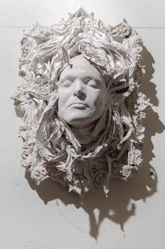 a paper sculpture of a man's head is shown in the middle of a white wall