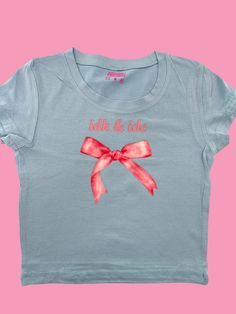 Girl, show your coquette dainty girly status with this IDK and IDC baby tee adorned with a beautiful pink coquette pink bow.  This stylish baby tee is the perfect way to let everyone know that you're literally just a girl. Made from a comfortable blend of 95% cotton and 5% spandex, this crop top is form-fitting and flattering for all body types. Available in a variety of colors to match your personal style. Please note that sizes run small, so be sure to check our sizing chart before ordering. D Bow Tee Shirt, Cute Cotton T-shirt With Bow, Pink Bow T-shirt With Short Sleeves, Casual Short Sleeve T-shirt With Pink Bow, Cute Cotton T-shirt With Pink Bow, Bow Crop Tops, Cropped Tops, Baby T Shirts, Stylish Baby