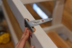 a person holding a pair of scissors in front of a wooden frame with wood flooring