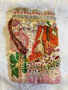 an embroidered purse is sitting on a white cloth