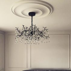 a chandelier hanging from the ceiling in a room with white walls and furniture