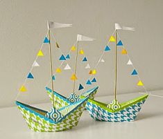 two paper boats with flags on them sitting next to each other