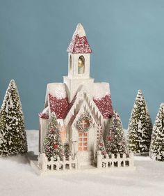 a small white church surrounded by snow covered trees