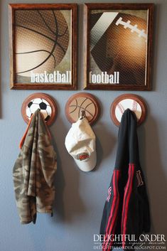 sports themed artwork hangs on the wall next to two coats and three hats hanging from hooks