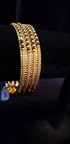 "* Handcrafted Gold Plated 4 Bangle Set. Sold as a set. * Bangles with pretty black beads and gold beads * High Quality 22 K Gold Plated- 4 Bangle set * Size 2.6 has 2.40\" inner circle diameter; Size 2.8 has 2.52\" inner circle diameter Gorgeous gold-plated bangle/ bracelet best exemplifies the careful craftsmanship done on it -- a specialty at Nemali Jewelry. It has a special tone of elegance attached to it. The intricate handmade design of the bangle/bracelet set gives it a fresh and original Gold Beaded Bangle Bracelets For Wedding, Black Bead Gold Bangles, Gold Beaded Bangle Jewelry, Black Bracelets For Festivals, Gold Bohemian Beaded Bracelets For Wedding, Elegant Gold Beaded Bracelets For Festivals, Bohemian Gold Beaded Bracelets For Wedding, Black Festive Bracelets For Festivals, Traditional Black Bracelets For Weddings