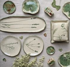 various plates and bowls are arranged on a tablecloth with flowers, leaves, and other items