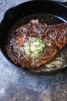 some meat is cooking in a skillet on a table with grated parmesan cheese