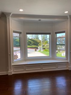 an empty room with wood flooring and large bay window overlooking the street in front of it