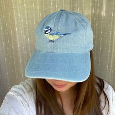 a woman wearing a blue hat with a bird on it's front and side