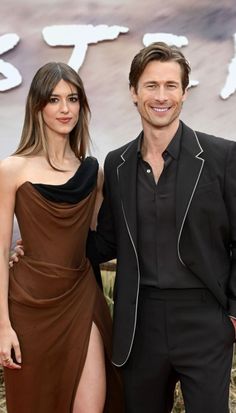 two people standing next to each other on a red carpet