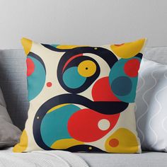 a colorful throw pillow sitting on top of a couch next to a gray pillow case