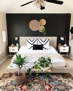 a bedroom with black walls and white bedding, potted plants on the floor