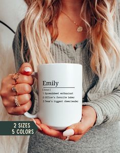 a woman holding a coffee mug with the words, family on it and two rings