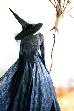 a black dress and hat on display in front of a tree with no leaves or branches