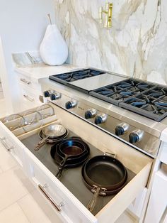 a stove top oven sitting inside of a kitchen next to a counter with pots and pans on it