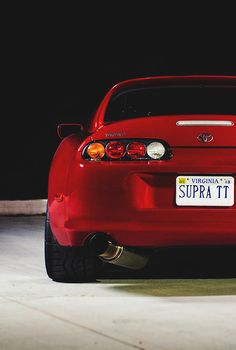 the back end of a red sports car parked in a parking lot with its license plate