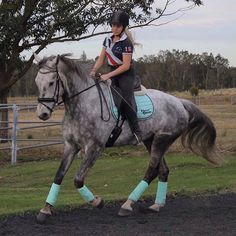 a woman riding on the back of a gray horse