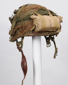 an old hat is sitting on top of a white pole with a brown bag hanging from it's side