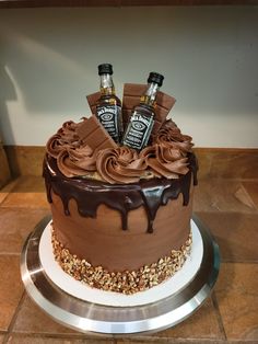 there is a cake with chocolate frosting and two bottles of whiskey on the top