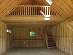 the inside of a building with wooden walls and stairs leading up to an upstairs loft