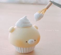 a cupcake with whipped cream on top and a whisk sticking out of it