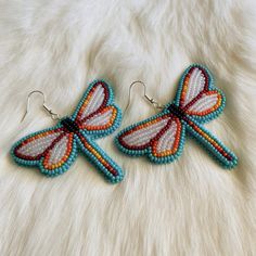 pair of beaded butterfly earrings sitting on top of a white furnishing surface