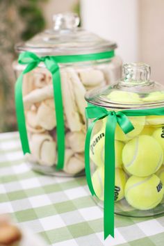 two glass jars filled with tennis balls on top of a table