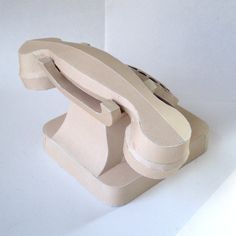 an object made out of cardboard sitting on top of a white table next to a wall