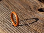 an orange ring sitting on top of a wooden table next to a hole in the wood