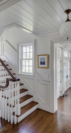 a white staircase with wood flooring and wooden handrails leading up to the second floor