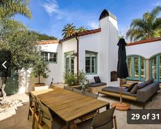 an outdoor patio area with table, couches and umbrella in front of the house