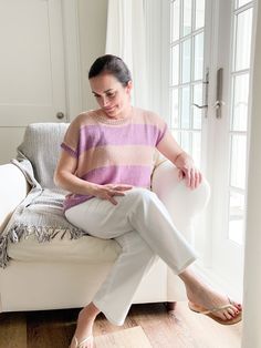 a woman sitting on a white couch in front of a window