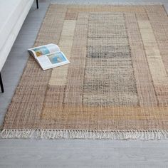 an area rug with fringes on the floor and a magazine laying next to it