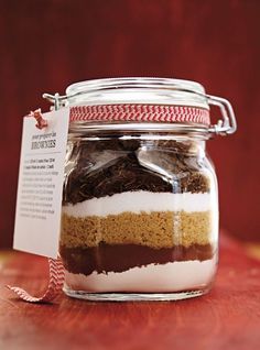 a glass jar filled with cake mix sitting on top of a wooden table next to a tag