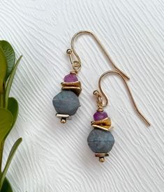 "The dainty size of these earrings makes them perfect for those who appreciate delicate and intricate jewelry. The carefully chosen beads, with their rich purple and delicate blue hues, lend a sense of mystique and depth to the earrings, making them an ideal choice for both casual and special occasions. Drop length: 1.5\" Width: .33\" Each Garnish and Grace piece is made in our home studio in the Finger Lakes region of New York State where we draw our inspiration from the surrounding countryside Purple Drop Earrings With Dangling Beads, Single Purple Drop Earring, Purple Single Drop Earring, Purple Dainty Earrings With Ear Wire, Dainty Purple Earrings With Ear Wire, Purple Jewelry With Dangling Beads For Gift, Blue Amethyst Dangle Earrings, Gift Purple Jewelry With Dangling Beads, Dainty Nickel-free Purple Earrings