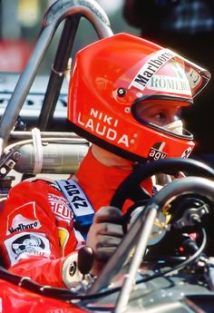 a man sitting in a race car wearing a red helmet and holding the steering wheel