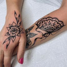 a woman's hand with tattoos on it and a flower tattooed on the wrist